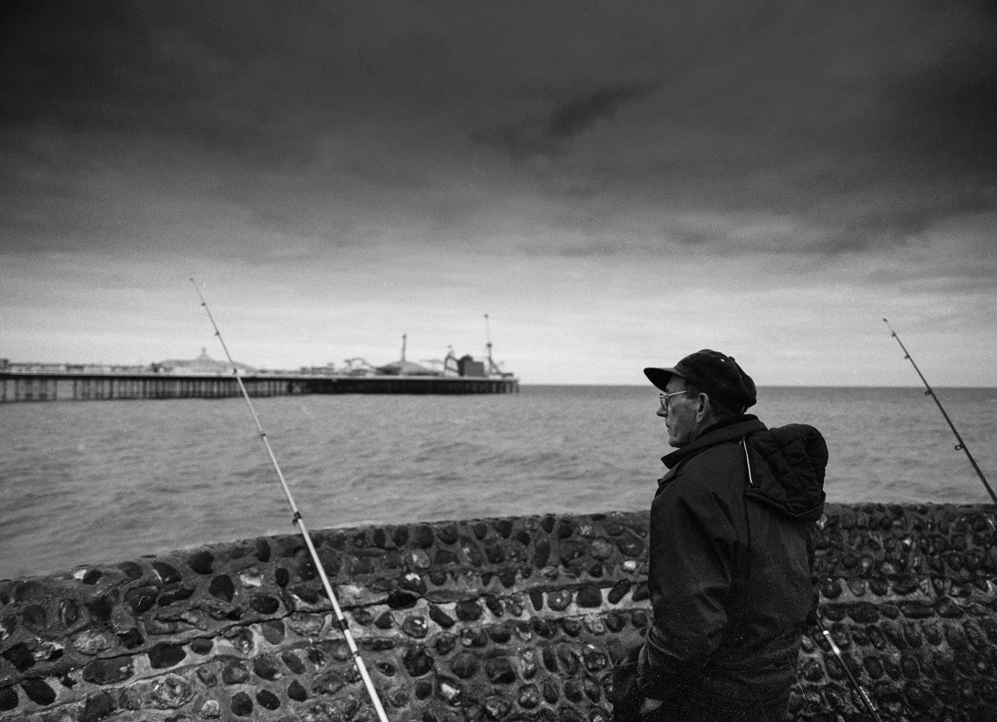 Un pescador solitario mira hacia el muelle de Brighton.